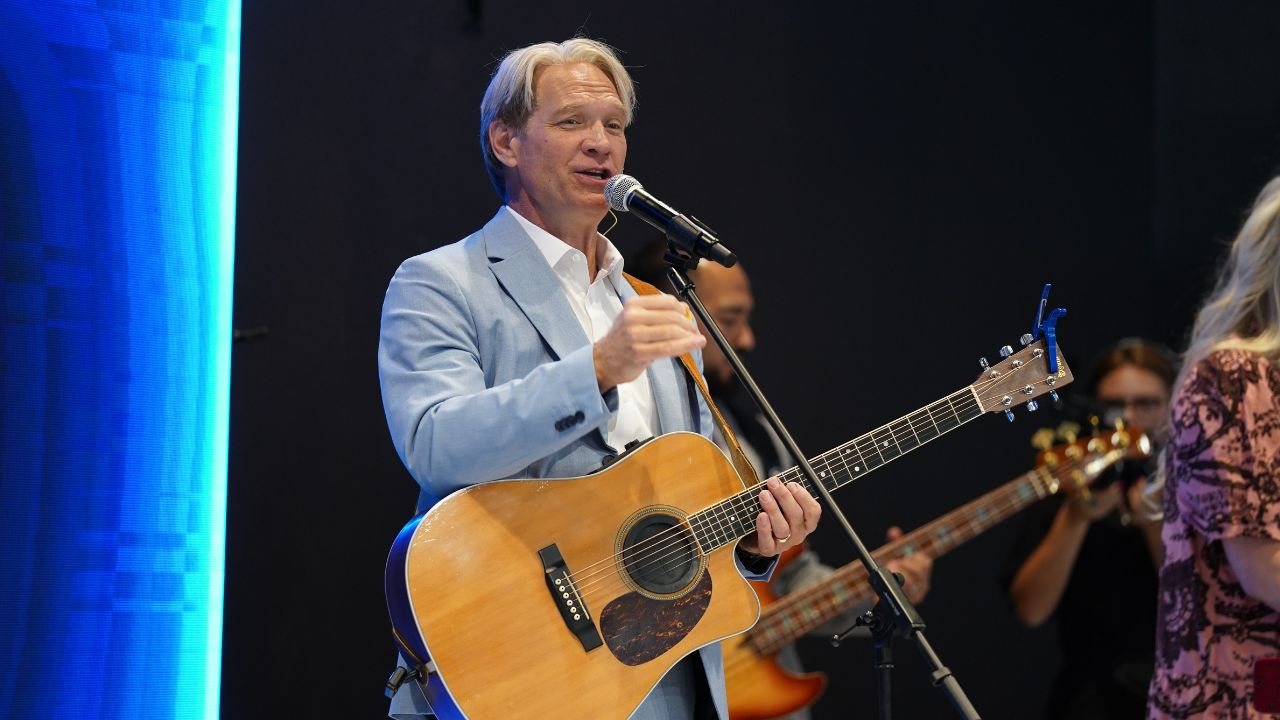 Pastor Stan Pody singing and playing acoustic guitar