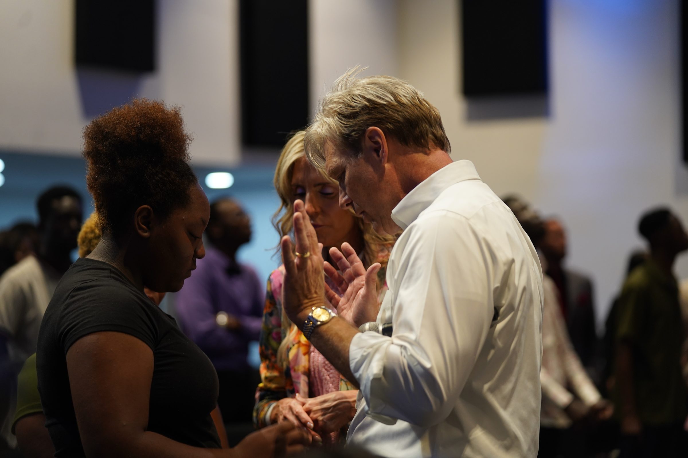 Pastor Stan Pody praying with a group at the front of a service