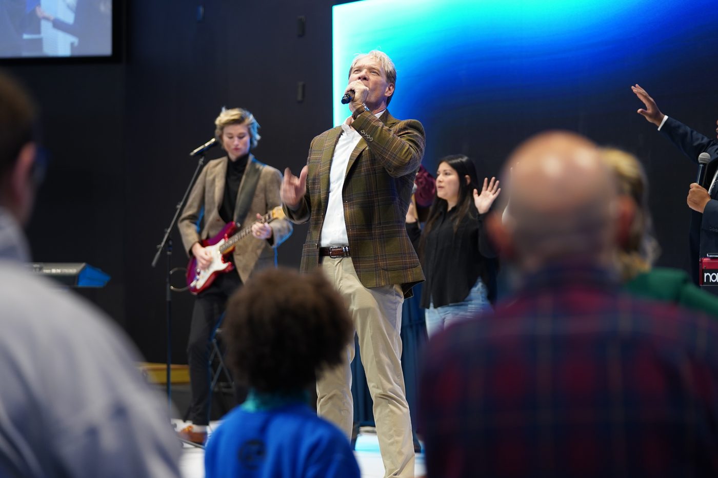 Pastor Stan Pody singing into a microphone during a service
