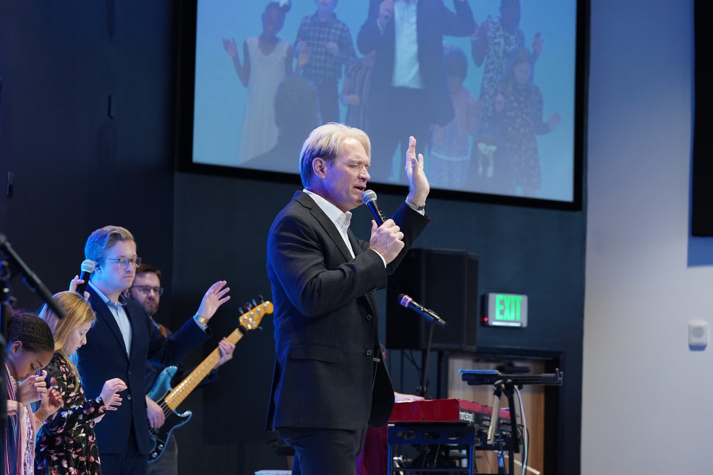 Pastor Stan Pody singing with his hand raised